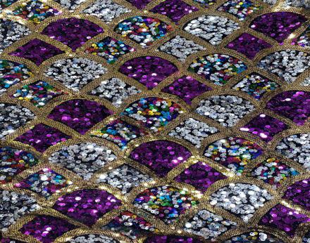 Tejido de terciopelo negro con lentejuelas en tonos platas, morados y multicolor.